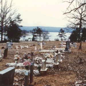 Rows of grave markers in cemetery with lake in the background