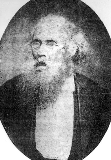 Old white man with glasses and long beard in suit