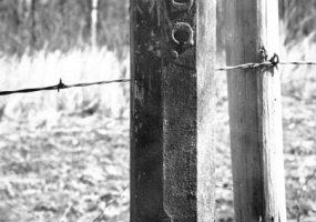 Barbed wire fence post with "Choc." written on it