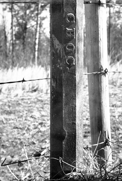 Barbed wire fence post with "Choc." written on it
