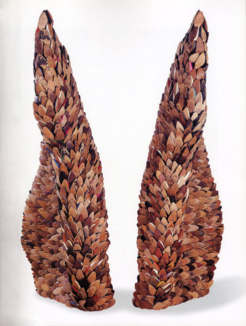 Large freestanding sculpture resembling wings made of found women's shoe soles on white backdrop