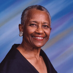 African-American woman with short hair and earrings smiling in low cut dress