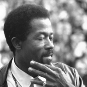 African-American man in white shirt and leather jacket holding his hand to his face