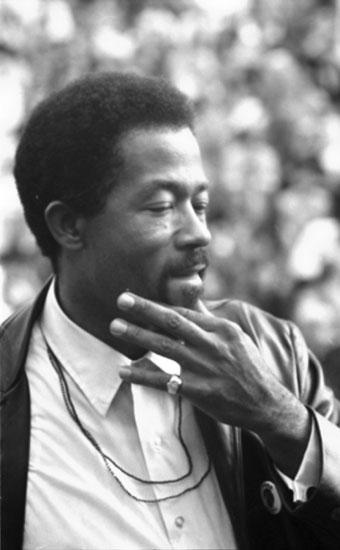 African-American man in white shirt and leather jacket holding his hand to his face