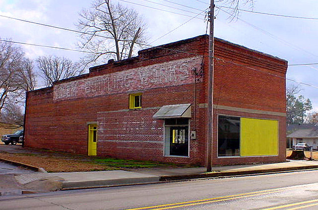 Brick storefront on street with faded words "Clem's Bottling Works" on its side