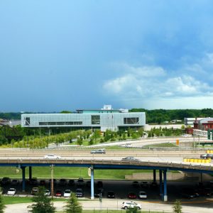 Various buildings viewed past raised highway with parked cars below