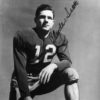 signed photo of white man in football uniform number 12 kneeling with right hand resting on helmet