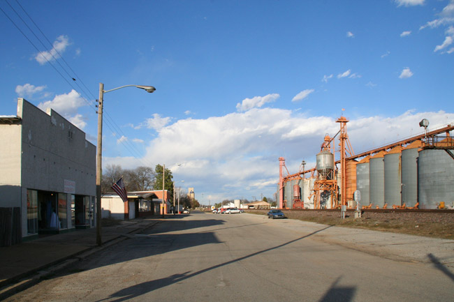 street with buildings on one side and silos on the other