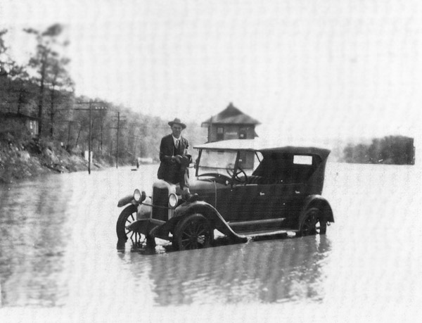 man sitting on car in flooded road