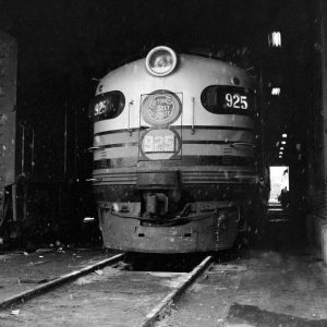 Locomotive with headlight and painted stripes with "cotton belt route 925" displayed on it parked in depot with snow flurries