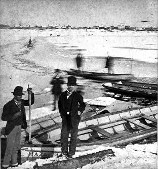 Men in dark suits and hats and rowboats on snowy river bank with other boaters pushing down icy rivulet