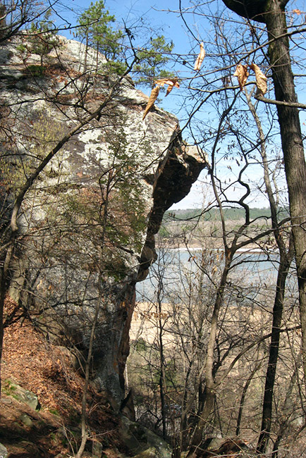 Rock face in wooded area with lake in the distance