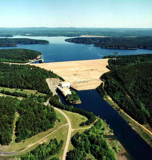 aerial view of lake with dam and tree covered shores