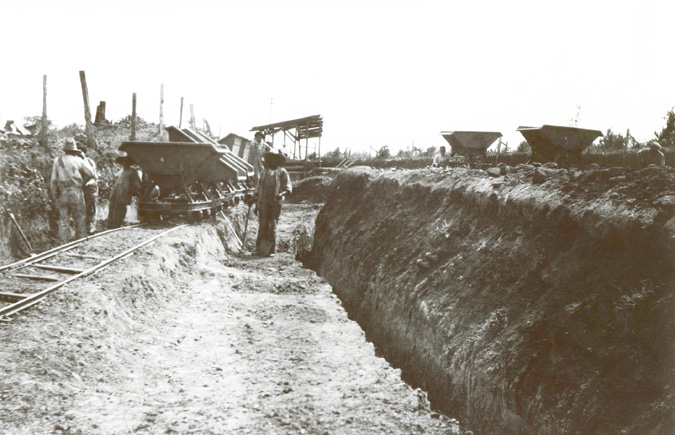 Miners digging trench with rail carts