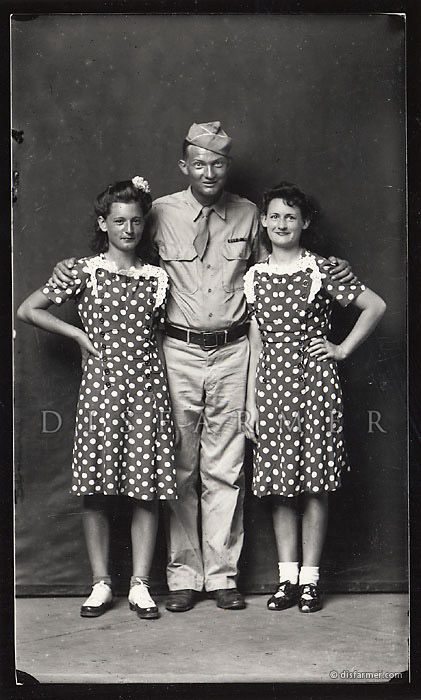 Portrait white male soldier with arms around two shorter white women matching polka dot dresses