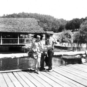 White man and woman performers on wooden bridge in park
