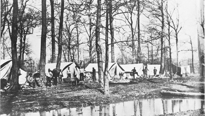 Men and tents with trees and hanging laundry