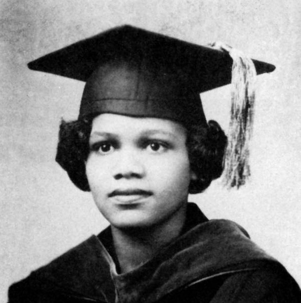 Young African-American woman in graduation robes and cap with tassel hanging on its left side