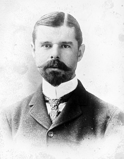 White man with beard and mustache in suit and tie