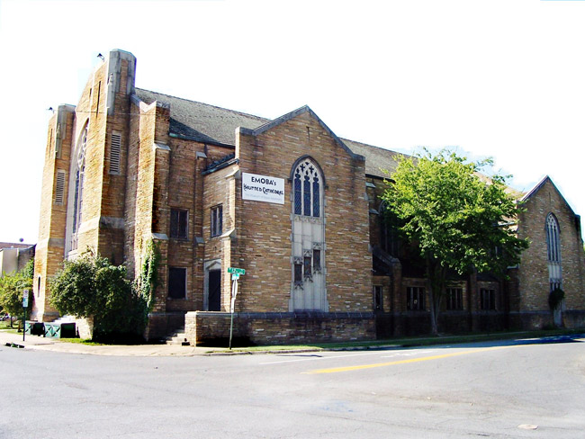 Multistory brick and stone church with arched stained glass windows and sign saying "Emoba's Haunted Cathedral"