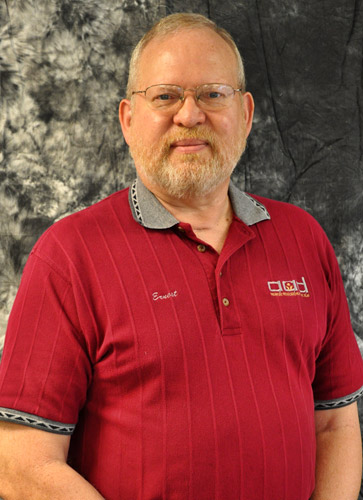 White man with glasses and beard in striped red collared shirt