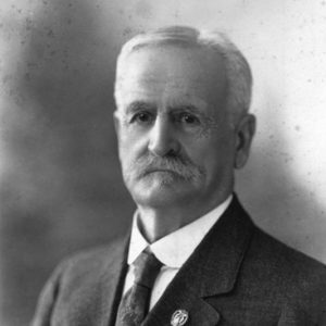 Older white man with mustache in suit and tie