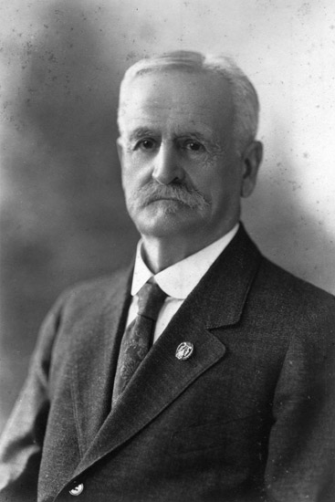 Older white man with mustache in suit and tie