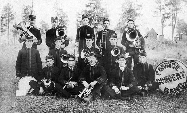 Group of young white men in uniform with brass instruments and "Fordyce concert band" drum