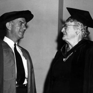 White man and woman smile chat in academic caps and gowns