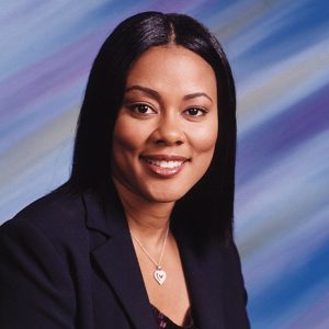 African-American woman smiling in suit jacket with heart necklace