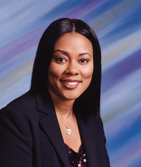 African-American woman smiling in suit jacket with heart necklace