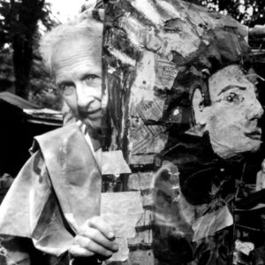 White man holding papier-mache mask in woods