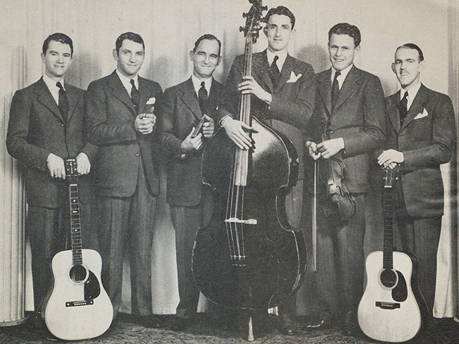 Group of white men in suits posing with musical instruments