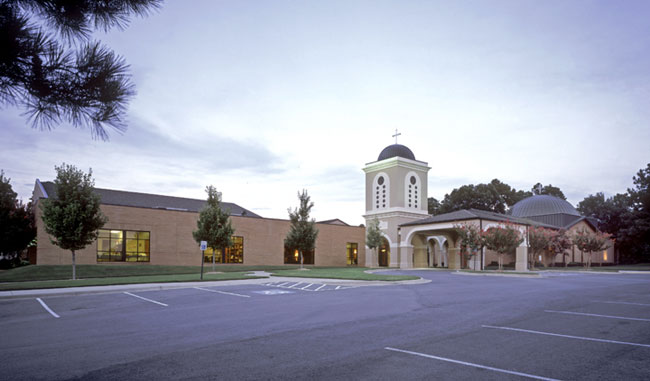 Single-story church with two-story tower and parking lot
