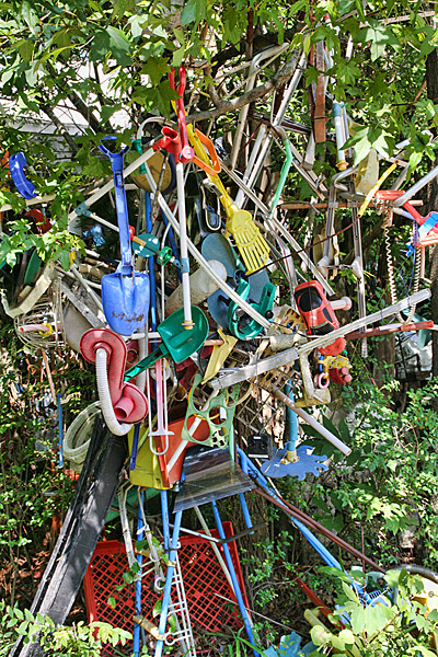 multicolored plastic gardening tools strung up with various other plastic items in tree