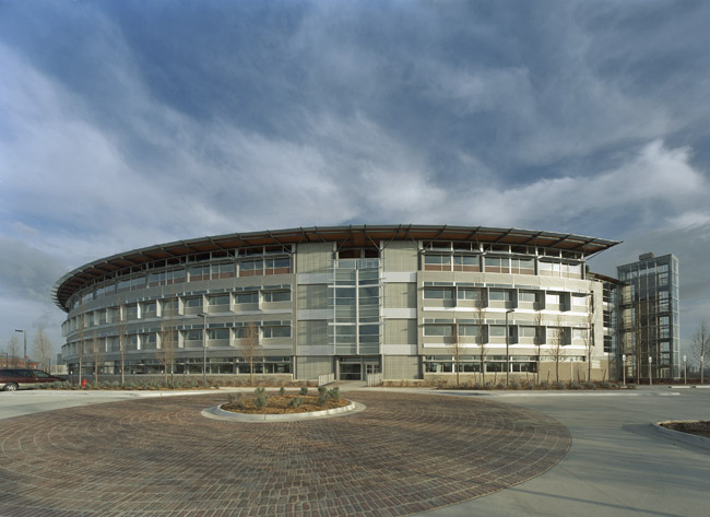 Four story curved architectural building with roundabout brick driveway and landscaping cloudy sky