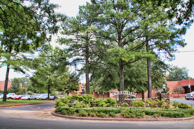 circular driveway with pine trees and sign in center "Hendrix College," buildings in background