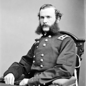 white man with mutton chops in military regalia sitting in chair
