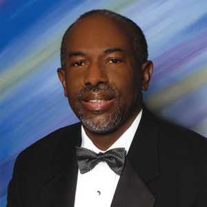 African-American man with beard and mustache smiling in tuxedo