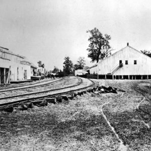 wooden buildings on either side of curved railroad tracks