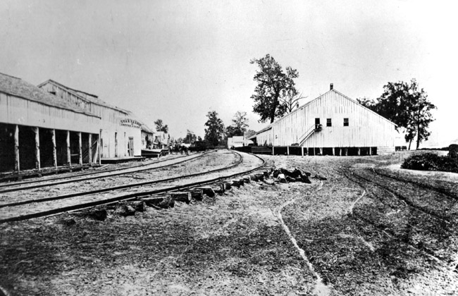 wooden buildings on either side of curved railroad tracks