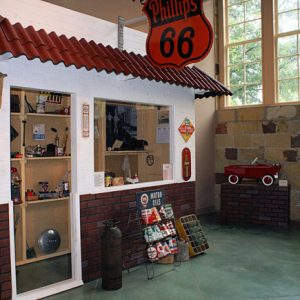 Model store front with shelves of various items and sign reading "Phillips 66"