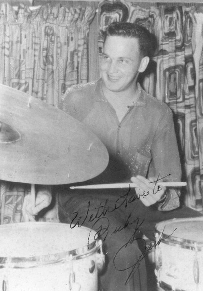 Signed photo of young white man playing drums in front of curtains