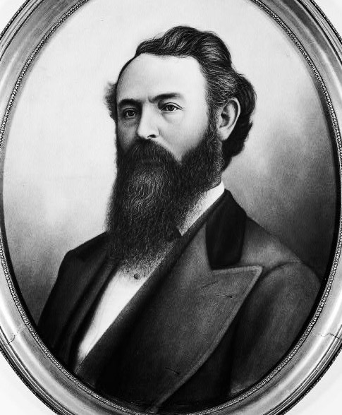 oval-framed portrait of a white man with dark hair and a long beard wearing a suit