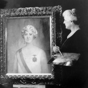 white woman painting portrait of white woman wearing sash and medal