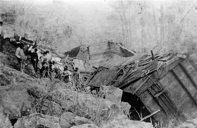 Seven men stand on rocky hillside near train wreck