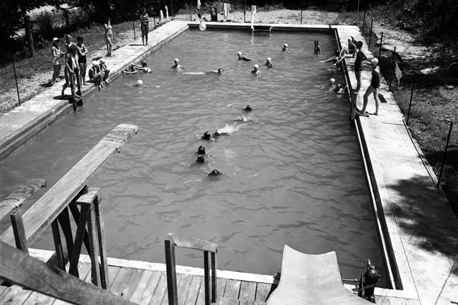 girls swimming in in-ground swimming pool with a diving board
