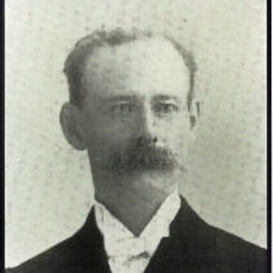 White man with bushy mustache in suit