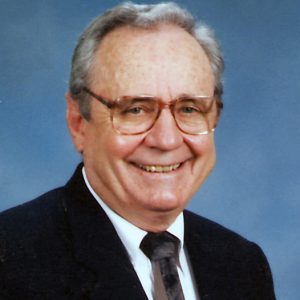 Portrait elderly white man smiling with short hair glasses suit and tie