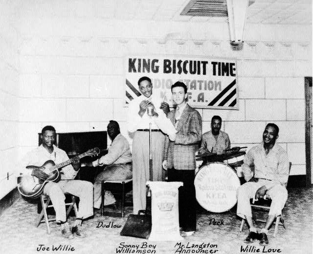 African American men play in a band in front of banner reading "King Biscuit Time"